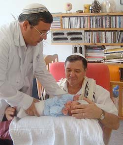Title: a mohel (standing) prepares the baby for circumcision